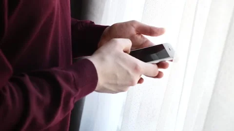Man standing next to the window and using mobile phone. Close up. Stock Footage 61281615