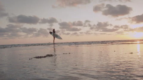 Man standing in the ocean with a surfboard at sunset Stock Footage 275163072