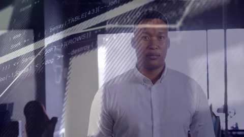 Man standing in office while live data starting code and graphs sweeping face Stock Footage 331634198