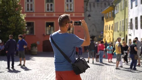 Man standing in the old town and doing photos of the architecture Stock Footage 103507652