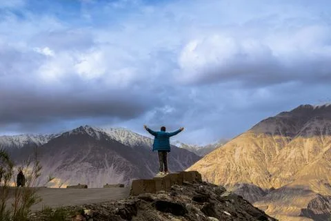 Man standing with open arms facing mountains. Stock Photos