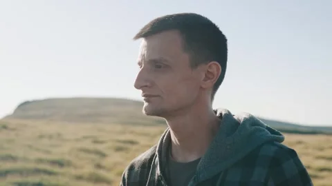Man standing in an open field with hills in the background on a clear day Stock Footage 343842245