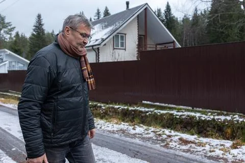 Man standing at open gate in snowy suburban yard Stock Photos