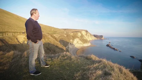 Man standing out looking towards durdle door in dorset Stock Footage 100879072