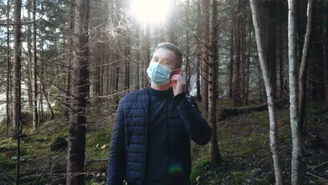 Man standing outdoors taking off a protective face mask while looking at camera Stock Footage 195446757