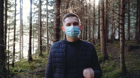 Man standing outdoors taking off a protective face mask while looking at camera Stock Footage 195447197