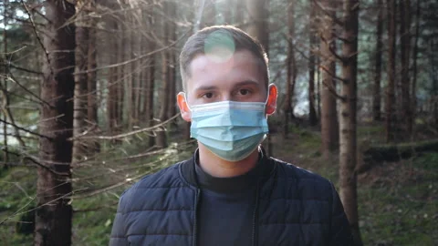 Man standing outdoors taking off a protective face mask while looking at camera Stock Footage 195447345