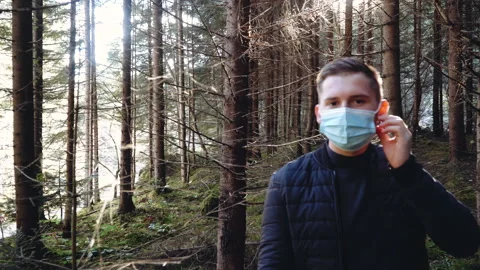 Man standing outdoors taking off a protective face mask while looking at camera Stock Footage 195447531