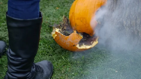 Man standing over smoking broken pumpkin outdoors - halloween mischief Video stock 115397729