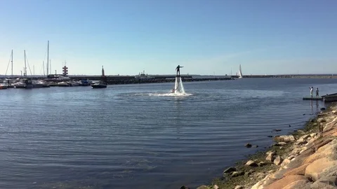 Man standing over the water on flyboard in the yacht harbor Stock Footage 85871567