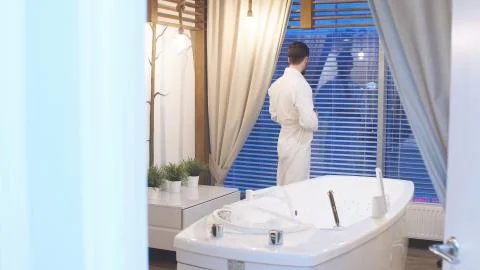 Man standing at a panoramic window with an evening view waiting for a Spa Stock Photos