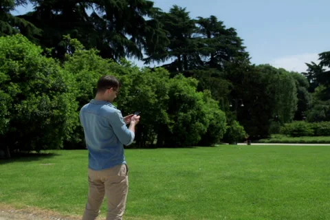 Man standing in the park and doing selfie on smartphone, steadycam shot Video stock 52779519