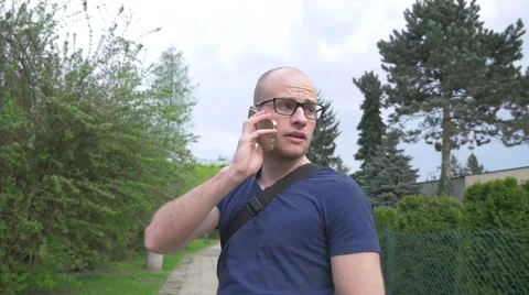 Man standing in the park, talking on the phone and looking around. Stock Footage 62520646