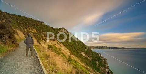 Man Standing On Path With Steep Cliff. Long Exposure. Nugget Point, Ciatlin.. Stock Photos