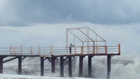 Man standing on pier during storm and big sea waves crashing. Storm at sea and Stock Footage 171552368