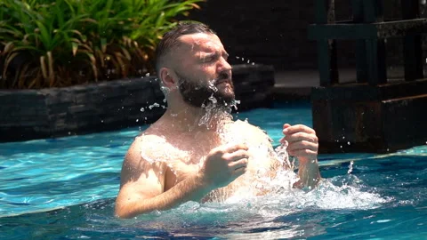 Man standing in the pool and splashing water on himself, slow motion Stock Footage 88539518