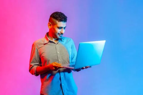 Man standing with portable computer in hand, looking at display, watching movie Foto stock