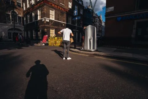 Man standing in the queue to use the public pissuar, urinal in Soho area. Stock Photos