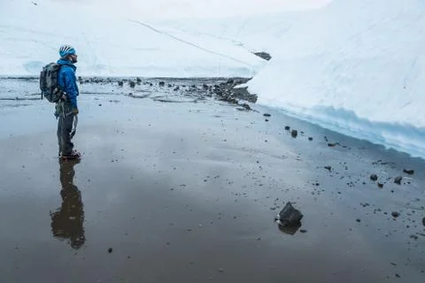 Man standing in the rain looking up at a large wall of ice on the Matanuska G Stock Photos