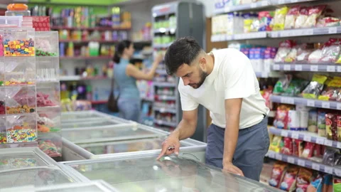 Man standing at refrigerator, choosing frozen convenience food in supermarket. Stock Footage 344776853