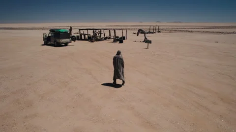 Man Standing in Remote African Desert with Vehicles and Structures Stock Footage 301368671