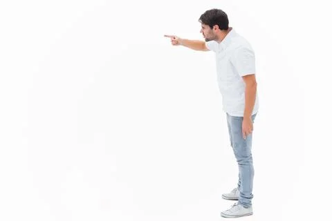 Man standing on right in white studio, leaning, pointing left in shirt, jeans, Stock Photos