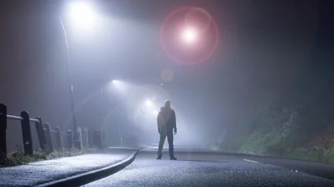 A man standing in the road. With a UFO floating in the sky at night Stock Footage 166446598
