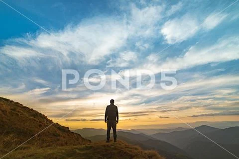 The man standing on the rock with a picturesque sunset Stock Photos