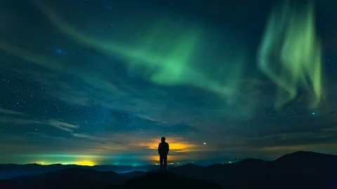 The man standing on the rock on the starry sky with a northern light background Stock Footage 97364024