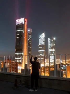 Man standing on rooftop looking at 4 Towers Business Center in Madrid at nigh Foto stock