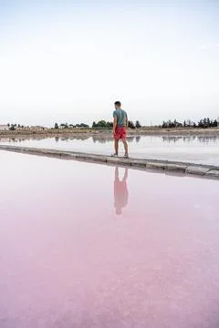 Man standing on salt flat divider with pink reflection Фото