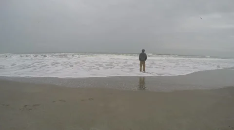 Man standing in the sand and looking out to the ocean. Stock Footage 62728617
