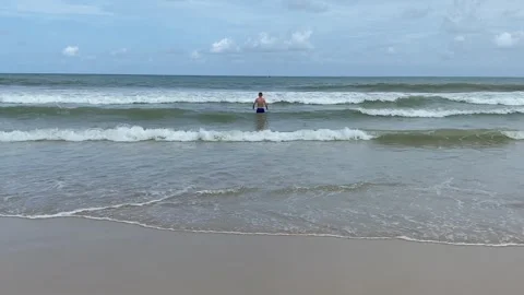 Man standing on sandy beachfront sunny ocean wave at coastline Stock Footage 278349449