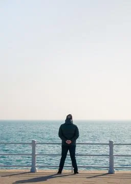 Man standing on the seafront and looking at the sea horizon Stock-Fotos
