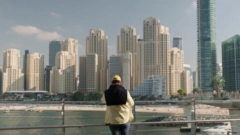 Man standing at seaside walkway with seafront view of Jumeirah beach Stock Footage 233783647
