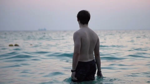 Man Standing in Shallow Ocean - Subtle Pink Colors Reflecting at Sunrise Stock Footage 126258548