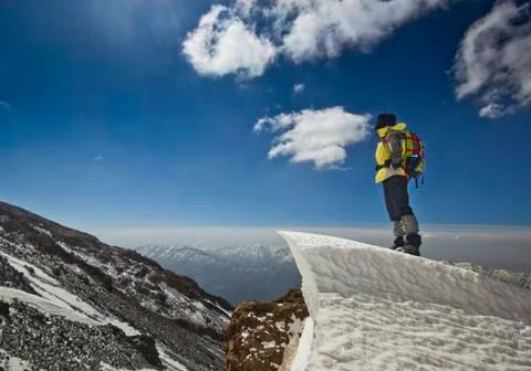 Man standing on a snow cornice in mountain sunrise Stock Photos