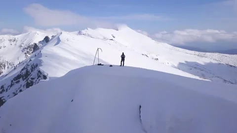 Man standing on snow covered mountain peak. View from drone orbiting Video stock 249054219
