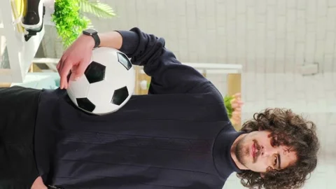 Man standing with soccer ball in front of the camera on bright room background. Stock Footage 153103244