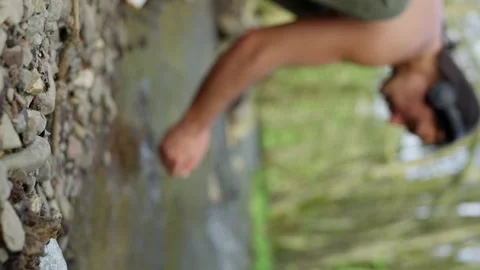 A man is standing by a stream, washing his hands. He looks content and at peace Stock Footage 275938415