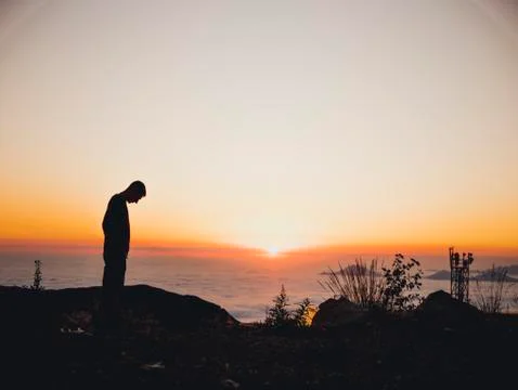 Man standing on the sunset clouds mountains sky skyline Stock Photos