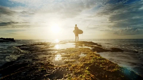 A man is standing with a surf in his hands on the sea shore. Видео 111614734