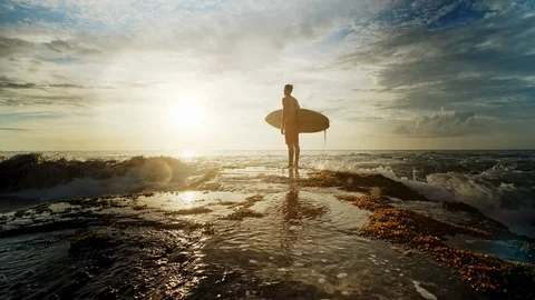 A man is standing with a surf in his hands on the sea shore. Видео 111615376