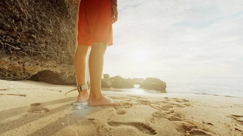 A man is standing with a surf in his hands on the sea shore. Stock Footage 111618422