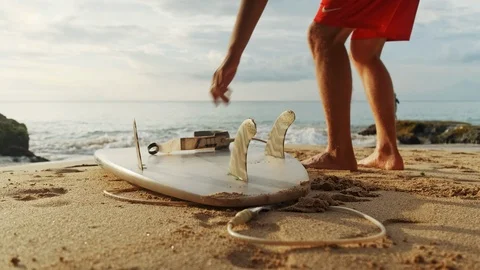 A man is standing with a surf in his hands on the sea shore. Видео 111619382
