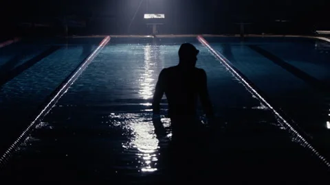 Man standing in a swimming pool under lighting at night Stock Footage 275260710
