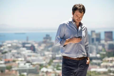 Man standing on the terrace using a mobile phone Stock Photos