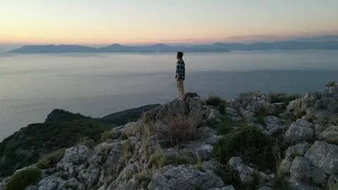 Man standing on the top of the mountain enjoying scenery sunset over sea Vídeo Stock 314214045