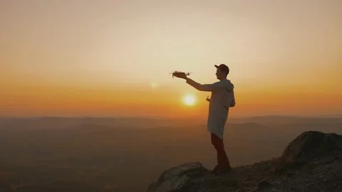 Man standing on top of mountain, starts drone from his hand, aircraft takes off Video stock 140355651