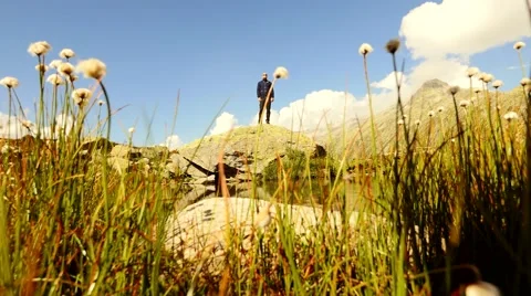 Man standing on top of stone surrounded by epic mountain lake scenery Stock Footage 64799680